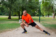 A sporty man is doing stretching exercises before running or workout outdoor in the summer park active healthy lifestyle. 