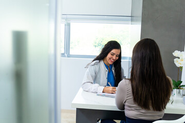 Hispanic female doctor or dentist hand writing medical prescription or notes of the patient in a notebook. Medical or dentistry concept.