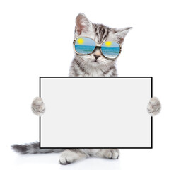 Poster - Tabby kitten wearing mirrored sunglasses shows blank white board. isolated on white background
