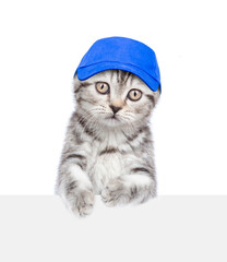 Poster - Cute kitten wearing blue cap looks above empty white banner. isolated on white background
