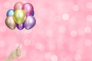 Aufkleber - Childrens hand holds bunch of colorful shiny balloons on blurred pink background. Empty space for text