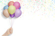 Female hand holds bunch of colorful balloons on white background with confetti. Empty space for text