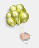 Fototapeta Psy - Childrens hand holding yellow or golden shiny balloons through the hole in white paper
