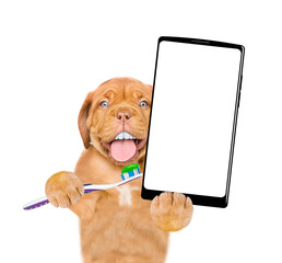 Poster - Mastiff puppy with funny big teeth holds the toothbrush with toothpaste and holds big smartphone with white blank screen in it paw. isolated on white background