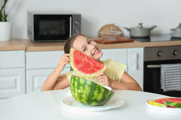 Sticker - Happy little girl with slice of fresh watermelon sitting at table in kitchen