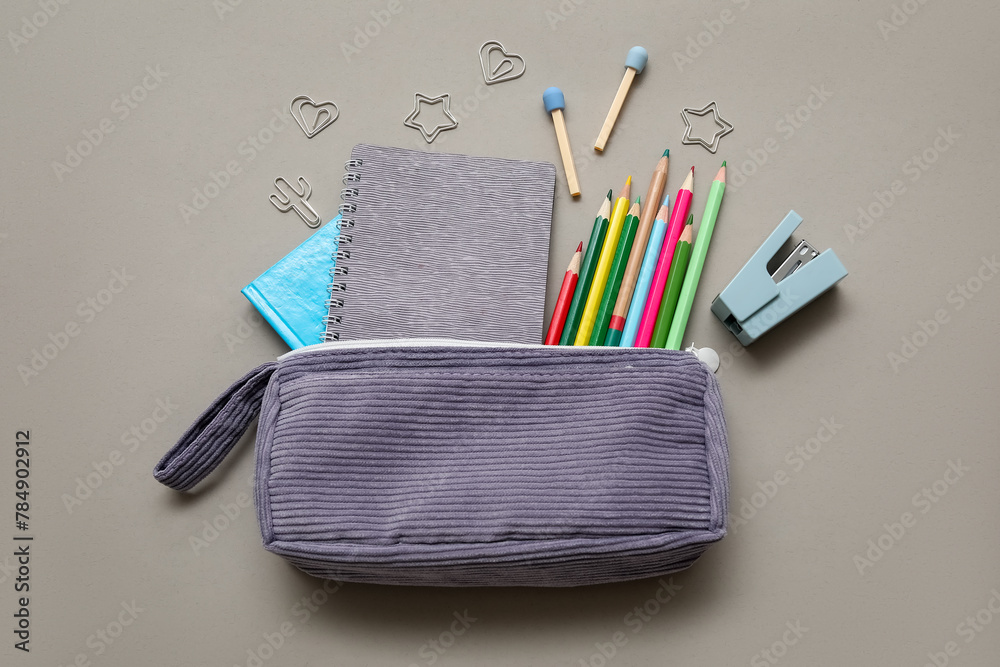 Purple pencil case with different school stationery and notebook on grey background