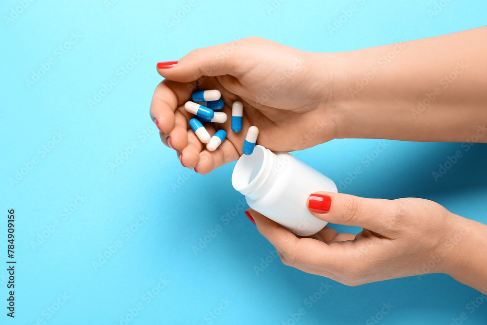 Female hands and bottle with pills on blue background