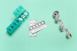 Container, blister packs with weight loss pills and measuring tape on turquoise background