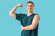 Young man with vaccination showing strength symbol with applied medical patch on blue background. Vaccination concept