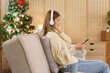 Christmas holiday concept, Women wearing headphone to listening music on phone near christmas tree