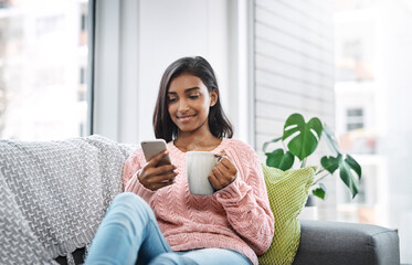 Wall Mural - Relax, coffee and girl on sofa with phone for social media, networking or streaming on weekend. Smile, connect and woman on couch with smartphone for communication, online chat or search in apartment