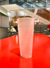 Wall Mural - An empty glass with a straw on a red table in a cafe