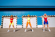 Young dance company in colorful swimsuits are dancing in the street. Three women go in for sports in the morning. Сoncept of sports, fitness, aerobics.