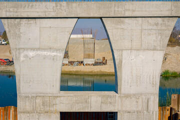 Look through huge pole in foundation with metal piles, construction of concrete-reinforced bridge pillars at building site over river