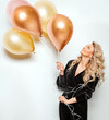 Beautiful Woman with Balloons over White background side view. Birthday Party Time. Happy smiling Blonde Model with Curly Hair style in Black Dress