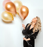Fototapeta  - Beautiful Woman with Balloons over White background side view. Birthday Party Time. Happy smiling Blonde Model with Curly Hair style in Black Dress