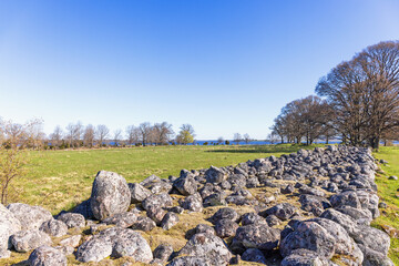 Wall Mural - Big stone wall on a field in a rural landscape at springtime