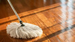 © Sunday Cat Studio - A mop head sweeping across a wooden floor, cleaning service and housework concept.