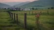 Selective focus on old wooden pole of wire fence on blur green grass field and city in valley.generativeai