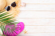 Vacation travel planning simple background of straw hat, sunglasses, palm leaves, flip flops and shells on white planks flat lay with copy-space