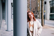 © Westend61 - Smiling woman leaning on column at footpath in city
