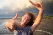 © Westend61 - Happy blond woman enjoying sunset making finger frames at beach
