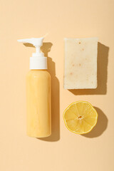 Wall Mural - Bottle with dispenser, bar of soap and lemon on beige background, top view