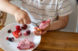 Un enfant mange un gâteau aux fruits rouges avec les mains dans une assiette blanche