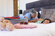 © Wavebreak Media - Biracial grandmother is tickling granddaughter on bed at home while packing for vacation