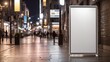 A blank billboard stands on a city street at night with blurred cars and people walking by

