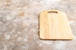 Empty rectangular wooden cutting board on brown concrete. Side view, copy space
