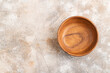 Empty brown wooden bowl on brown concrete. Top view, copy space