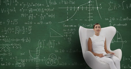 Poster - Image of a smiling Caucasian woman wearing white clothes sitting in a white chair using a tablet com