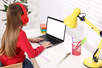 Sticker - E-learning. Girl using laptop and headphones during online lesson at table indoors