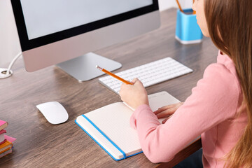 Wall Mural - E-learning. Girl taking notes during online lesson at table indoors, closeup