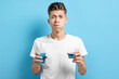 Young man using mouthwash on light blue background