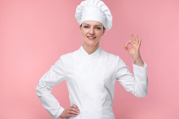 Canvas Print - Happy chef in uniform showing OK gesture on pink background