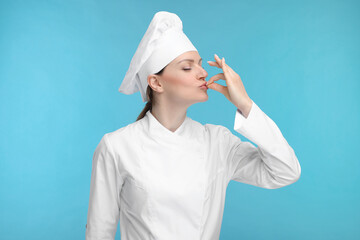 Canvas Print - Woman chef in uniform showing perfect sign on light blue background