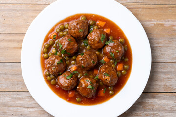 Canvas Print - Meatballs, green peas and carrot with tomato sauce on wooden table. Top view