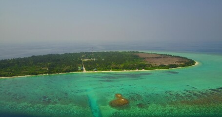 Aerial view of turquoise water by an island with trees in the Maldives