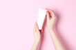Woman holding tube of cream on pink background, closeup