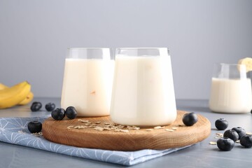 Tasty yogurt in glasses, oats and blueberries on grey table