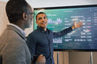 © ReeldealHD images - Young businessman presenting performance data to senior businessman on a large screen