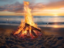 A Fire Is Burning On A Beach, With A Couple Of Sticks In The Fire. The Fire Is Surrounded By Logs And The Beach Is Calm And Peaceful