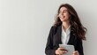 © yj - Portrait of happy young business woman in suit using digital tablet while standing over white background with copy space, smiling and looking away. generative AI