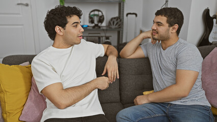 Two men conversing comfortably on a sofa in a modern living room.