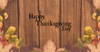 Image of happy thanksgiving day text over wooden background with autumn leaves
