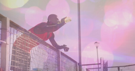 Wall Mural - Image of light spots over african american man drinking water at beach