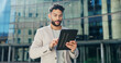 © peopleimages.com - Building, city and tablet with business man outdoor in summer for morning commute or research. Email, internet and social media with confident young corporate employee in urban town for travel