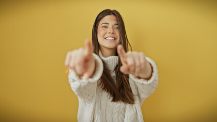 Sticker - A cheerful young hispanic woman in a sweater, pointing to the camera against a yellow background.